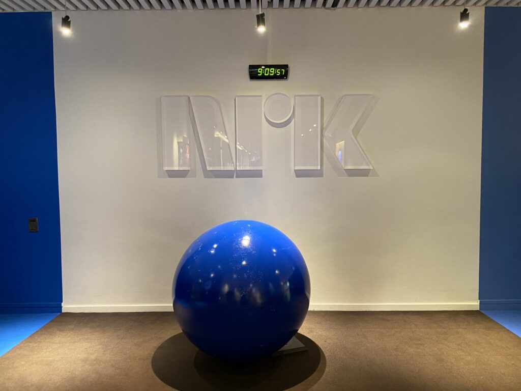 NRK logo on a white wall above a large blue sphere